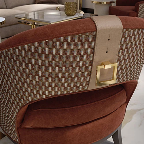 Close view of a contemporary armchair outside back, upholstered in pattern fabric, with beige leather insert embellished by a custom gold plated metal handle